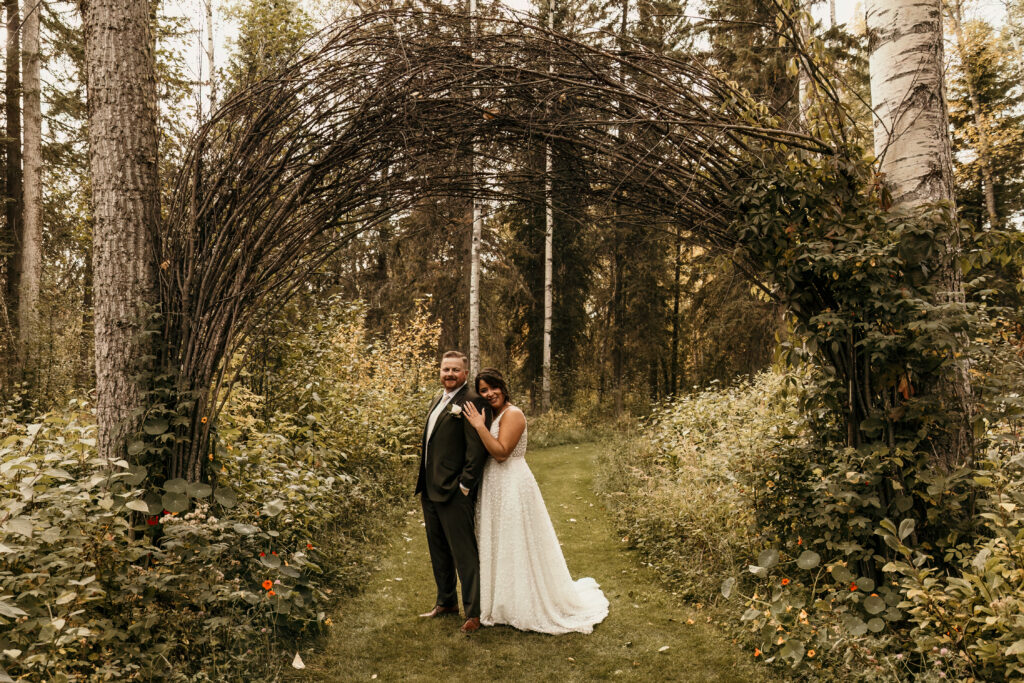 Bride and groom standing under an arch made out of tree branches