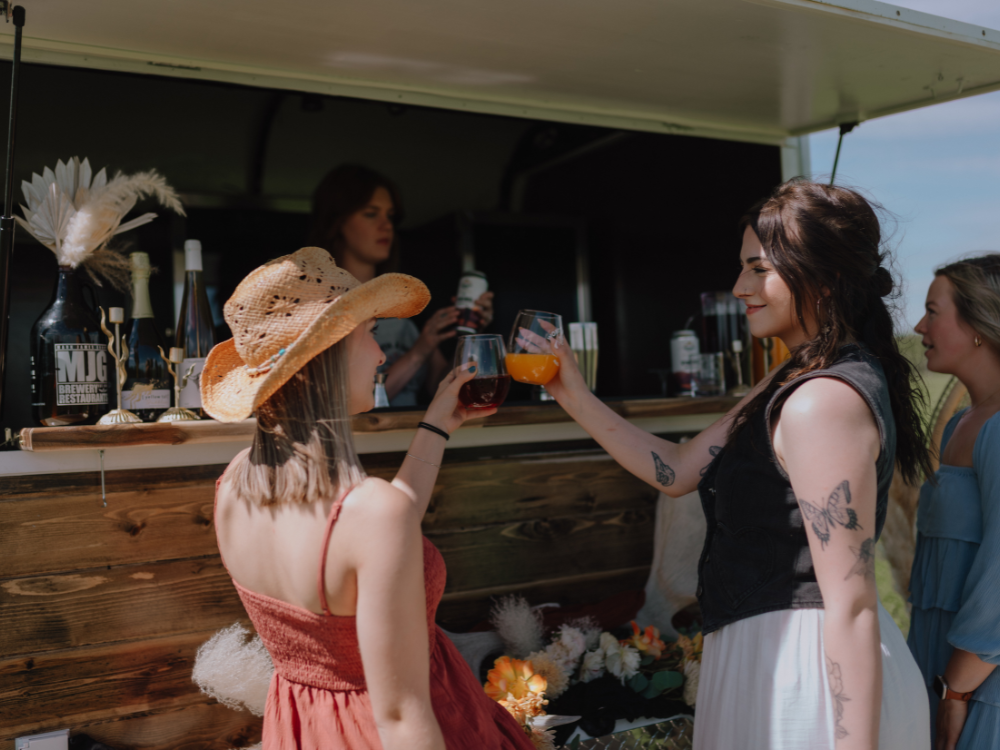 A group of women in front of a mobile bar trailer