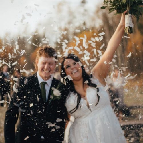 A bride and groom celebrating with white confetti around them