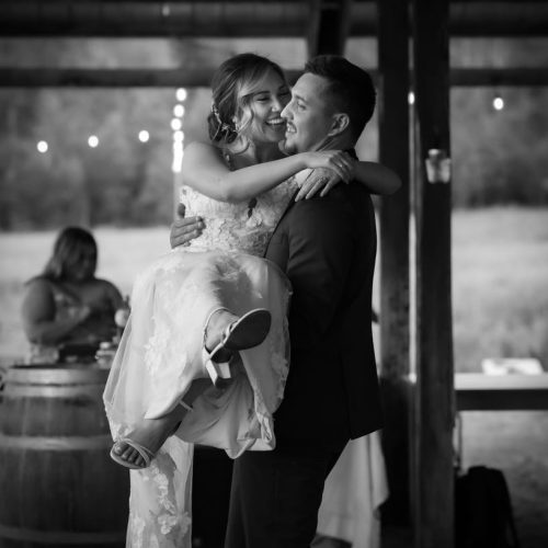 A man holding a women in a wedding dress in his arms